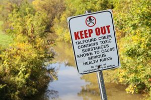 A sign warns the public of toxic pollution in the water due to the chemical plants.